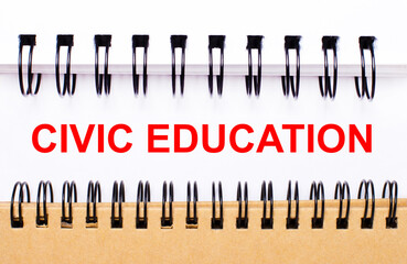 Text CIVIC EDUCATION on white paper between white and brown spiral notepads.
