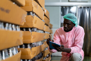 African American male factory worker using notes inspecting goods or product of Basil seed with...