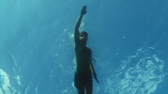 Persona nuota nel mare in stile libero visto da sott'acqua