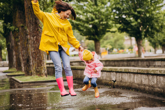 Mother with daughter having fun jumping in puddles