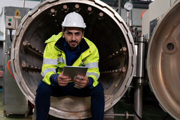 Fototapeta na wymiar Male factory mechanic. Male engineer working with digital tablet for repairing, maintenance and checking steam boiler and automatic controls systems in the beverage factory. factory, industry concept