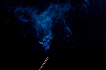 black background, two incense sticks. there is smoke, smell, incense. close-up.