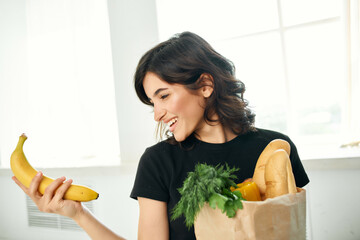 cheerful woman package with groceries in the kitchen healthy food homework