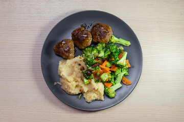 A plate of meatball with vegetables and mashed potato.