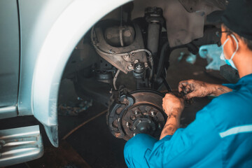 Young man using tool for repair brake car a part of wheel tire in garage.