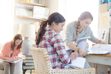 Three teenage girls doing homework in room
