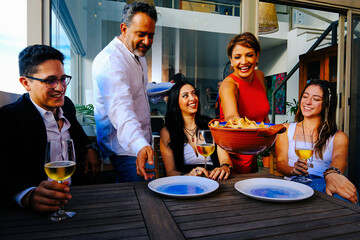 Happy family. Cheerful parents serving dinner to smiling children sitting at table