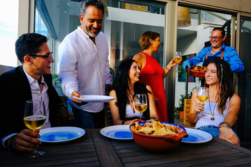 Cheerful family serving food to children sitting at table during reunion at home