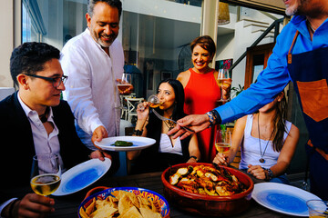 Cheerful men and woman with children enjoying dinner together at home