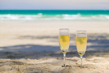 Two glasses of champagne on sand beach