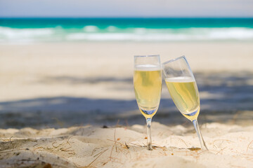 Two glasses of champagne on sand beach