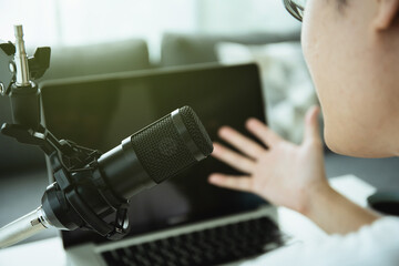 Unrecognizable Asian young man making a home podcast or online radio live streaming.