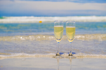 Two glasses of champagne on sand beach