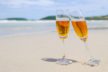 Two glasses of champagne on sand beach