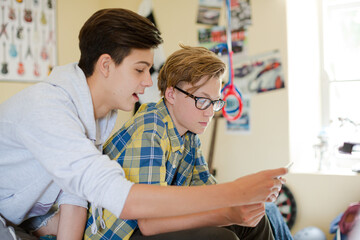 Obraz premium Two teenage boys having fun while using digital tablet