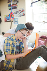 Fototapeta premium Two teenage boys using electronic devices in room