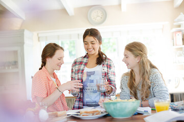 Teenage girls learning at table in kitchen