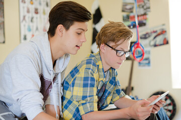 Two teenage boys having fun while using digital tablet