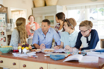 Teenagers with mid adult man sitting at table in dining room
