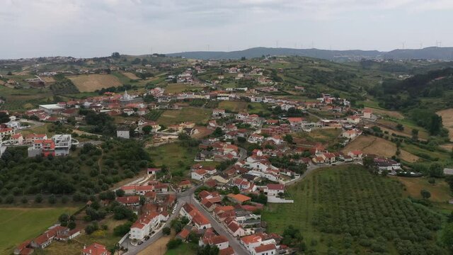 Drone flight over green farmland and houses Batalha village, agriculture and rural life in Portugal
