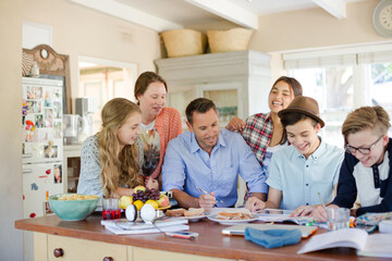 Teenagers with mid adult man sitting at table in dining room