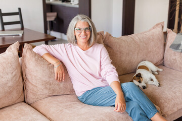 Portrait happy healthy middle aged woman sitting on comfortable couch at home