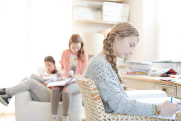 Three teenage girls doing homework in room