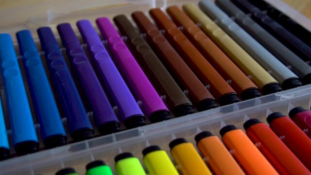 Colored markers are on the table. Stationery. Plastic box. Creative tool. Felt-tip pens for drawing. View from above.