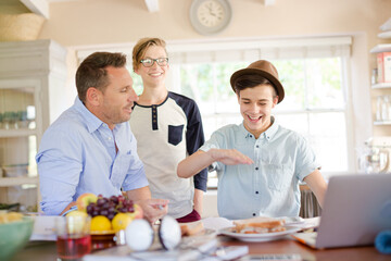 Mid adult man watching teenage boys doing high five