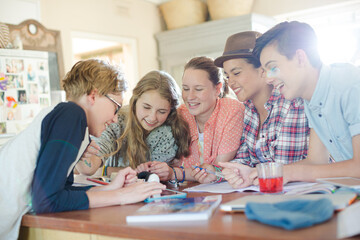 Group of teenagers using together digital tablet at table in kitchen