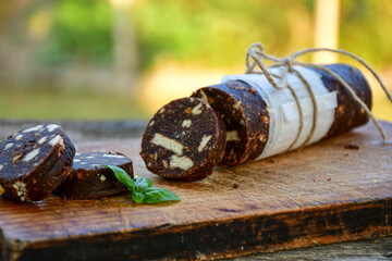 Homemade delicious  traditional Italian dessert Chocolate salami cake  with walnuts and biscuits on  wooden ackground. 