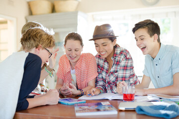 Fototapeta premium Group of teenagers using together digital tablet at table in kitchen