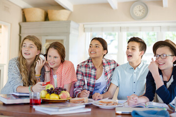 Fototapeta premium Group of smiling teenagers gathered around table in dining room