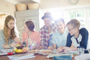 Group of smiling teenagers gathered around table in dining room