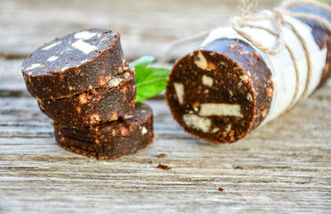 Homemade delicious  traditional Italian dessert Chocolate salami cake  with walnuts and biscuits on  wooden ackground. 