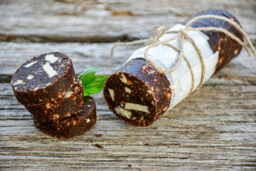 Homemade delicious  traditional Italian dessert Chocolate salami cake  with walnuts and biscuits on  wooden ackground. 