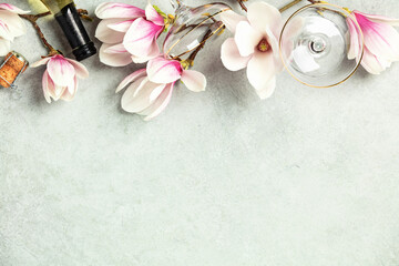 Beautiful flat lay with spring magnolia flowers, wine and glasses on grey stone background