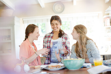 Teenage girls learning at table in kitchen