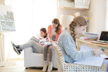Three teenage girls doing homework in room