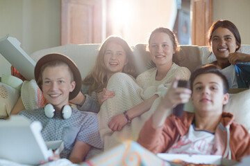 Group of teenagers watching tv on sofa together
