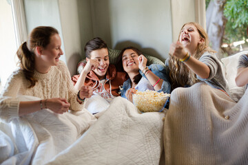 Group of teenagers throwing popcorn on themselves on sofa