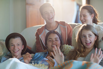 Group of teenagers having fun while watching tv on sofa