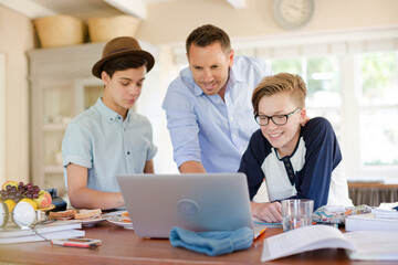 Fototapeta na wymiar Teenage boys with father using laptop in dining room