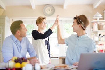 Mid adult man watching teenage boys doing high five