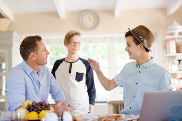 Mid adult man watching teenage boys doing high five