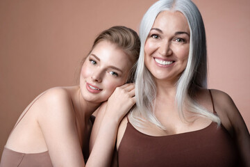 Beautiful female generations, happy family, mature mother, adult daughter embracing smiling looking at camera spend time together. Natural woman beauty. Mother's Day concept.