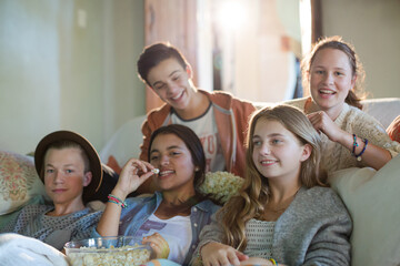 Group of teenagers having fun while watching tv on sofa