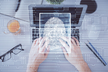 Double exposure of man's hands typing over computer keyboard and finger print hologram drawing. Top view. Personal security concept.