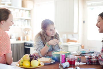Teenage girls learning at table in kitchen
