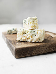 French cheese with blue mold. Dor blue on a wooden board. French cuisine on a light background. Gorgonzola. Space for the text.